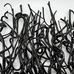 May include: A tangled pile of black, flexible, wire-like material. The material is twisted and bent into various shapes, creating a chaotic and abstract design.