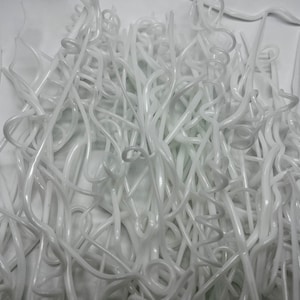 May include: A pile of white plastic hangers, tangled and intertwined. The hangers are all the same shape and size, and they are made of a thin, flexible plastic.