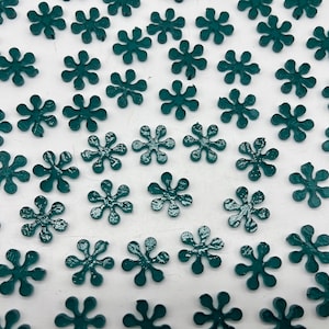 May include: A collection of teal blue star-shaped embellishments scattered on a white surface.