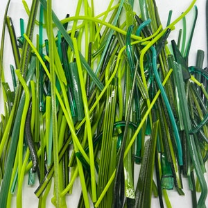 May include: A collection of green glass rods in various shades of green, including lime green, forest green, and teal. The rods are arranged in a random pattern, creating a visually appealing display.