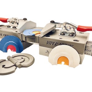 May include: A silver-colored reed-making tool with red handles and the text "VIPER PRESS" and "THE ORIGINALS". Includes several reed-shaped components in blue, white, and orange.