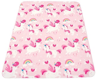 May include: Pink play mat with a repeating pattern of white unicorns with pink wings and rainbow arcs. The unicorns are surrounded by pink hearts.
