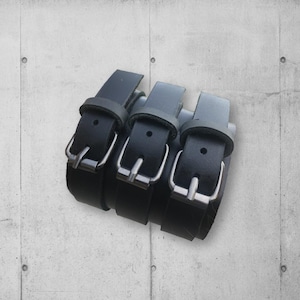 May include: Three black leather bracelets with silver buckles. The bracelets are stacked on top of each other.