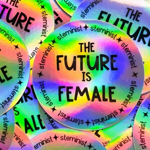 Może przedstawiać: Okrągłe naklejki holograficzne z napisem "THE FUTURE IS FEMALE" w kolorze czarnym. Naklejki mają efekt tęczy, a słowo "steminist" jest wydrukowane na krawędzi. Naklejki są okrągłe.