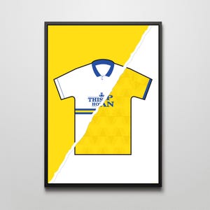 Puede incluir: Una camiseta de fútbol blanca y amarilla con cuello azul y una franja azul a través del pecho. La camiseta tiene el texto "This Is How You Do It" en la parte delantera.