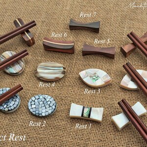 Puede incluir: Diez estilos diferentes de reposabajos, hechos de madera y madreperla. Los reposabajos est&aacute;n dispuestos sobre un fondo de arpillera. El texto "Select Rest" est&aacute; en la parte inferior de la imagen.