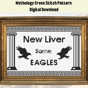 Könnte beinhalten: Ein schwarz-weißes Kreuzstichmuster in einem goldenen Rahmen mit dem Text "New Liver Same Eagles" und zwei schwarzen Adlern auf beiden Seiten des Textes.