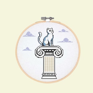 Puede incluir: Un gato blanco sentado en la parte superior de una columna blanca con una base azul. La columna tiene una parte superior y una inferior decorativas. El gato mira hacia la derecha. El fondo es azul claro con nubes blancas.