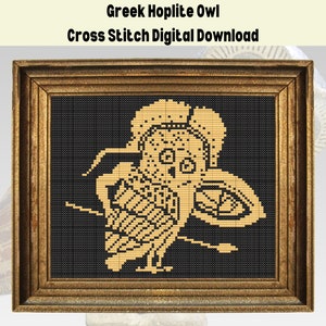 Puede incluir: Un patrón de punto de cruz de un búho hoplita griego en oro sobre un fondo negro. El búho lleva un casco y sostiene un escudo. El patrón está enmarcado en un marco dorado.