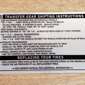 May include: Black and white sticker with instructions for a transfer gear shifting system. The sticker includes instructions for both automatic and manual transmissions, as well as instructions for replacing tires. The sticker has the text "20 Transfer Gear Shifting Instructions" at the top.