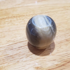 May include: A round, smooth, black and white, marbled,  decorative knob.