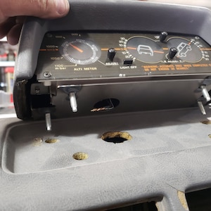 May include: A black dashboard gauge with a silver face and orange markings. The gauge has three dials, one for altitude, one for pitch, and one for roll. The gauge also has a warning label that reads "WARNING: ACCURATE ONLY WHEN COMPLETELY LEVEL - DO NOT EXCEED 20 DEGREES."