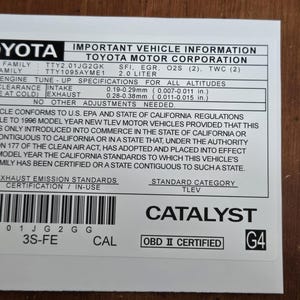 May include: A white sticker with black text that reads "TOYOTA IMPORTANT VEHICLE INFORMATION TOYOTA MOTOR CORPORATION" and includes details about the vehicle's engine, emissions, and compliance with US EPA and California regulations. The sticker also includes the text "CATALYST OBD II CERTIFIED G4".