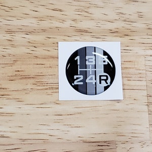May include: A black and white gear shift pattern sticker with the numbers 1, 2, 3, 4, 5, and R.