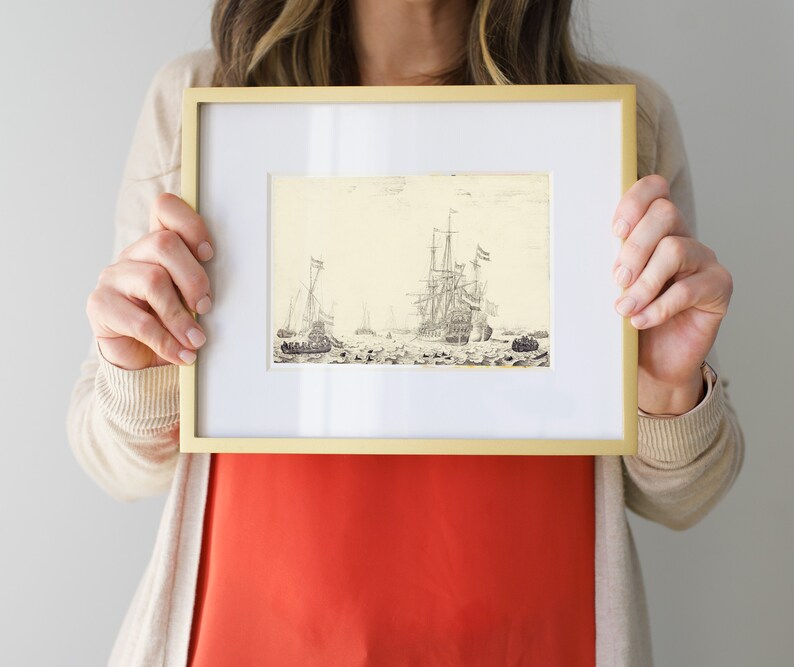 May include: A framed black and white drawing of a fleet of ships sailing on the water. The ships have sails and masts. The drawing is in a gold frame.
