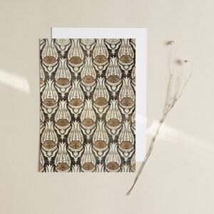 May include: A white card with a black and white print of a repeating pattern of stylized tulips. The tulips are outlined in black and have a brown and white center. The card is on a beige background.