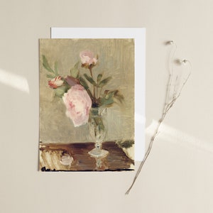 May include: A painting of a bouquet of pink peonies in a glass vase on a wooden table.