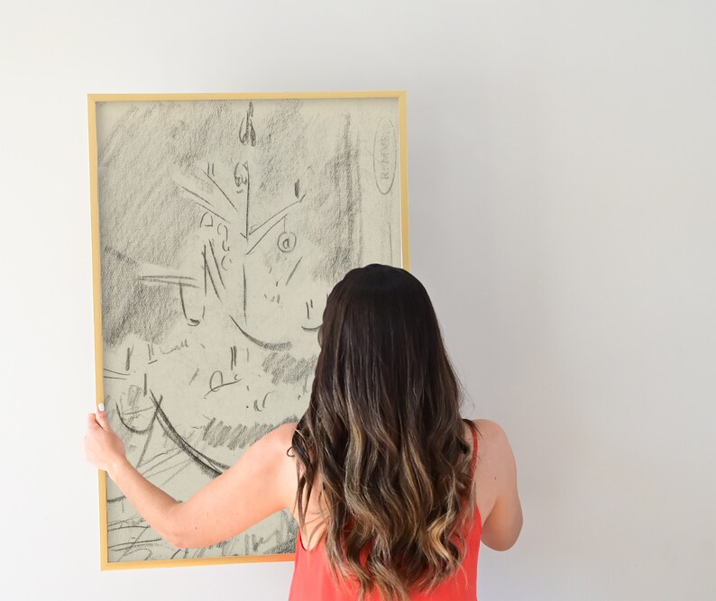 Peut inclure: Un croquis au fusain encadr&eacute; d'un sapin de No&euml;l. L'&oelig;uvre est dans un cadre dor&eacute; et tenue par une personne. L'esquisse est dans des tons de gris et de noir, avec un style minimaliste. Le fond est un mur blanc uni.