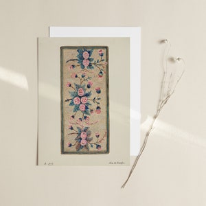 May include: A vintage needlepoint design featuring a floral motif with pink roses and green leaves on a cream background. The design is framed in a dark blue border.