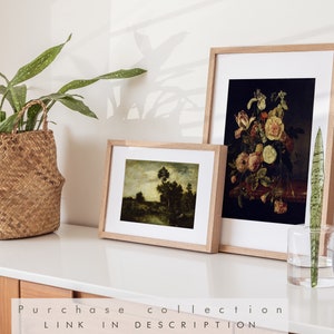 May include: Two framed art prints on a white surface. The print on the left is a landscape painting with a river and trees. The print on the right is a still life painting of flowers in a vase.