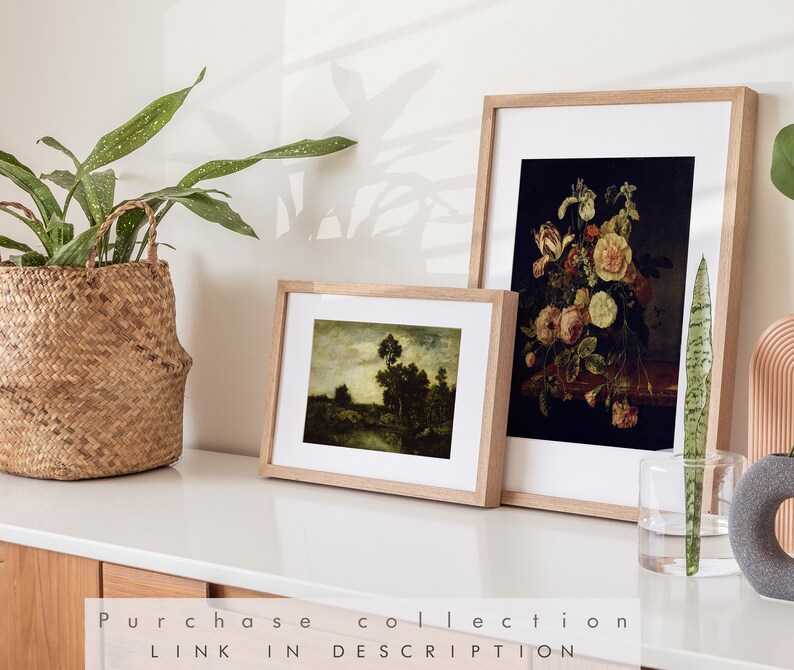 May include: Two framed art prints on a white surface. The print on the left is a landscape painting with a river and trees. The print on the right is a still life painting of flowers in a vase.