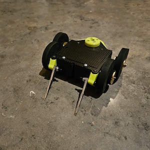 May include: A small, yellow and black robot with four wheels and two long, thin, metal arms. The robot is made of carbon fiber and has a black base with a yellow top.