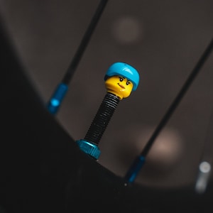May include: A blue and yellow Lego figure valve stem cap for a bicycle tyre.