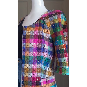 May include: A multi-coloured quilted jacket with a patchwork design. The jacket has a white trim and is adorned with sequins.