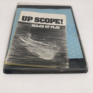 May include: A vintage board game called "Up Scope!" with a black and white illustration of a submarine on the cover. The game includes rules of play and a game board.