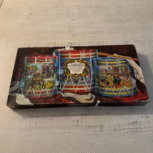 May include: A vintage board game box featuring three colorful toy drums with illustrations of military scenes. The box is brown with a gold border and the text "The American Campaign" is printed on the front.