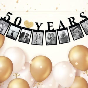 May include: Black and white photo banner with gold glitter heart and the text "50 YEARS". The banner is strung with black string and has 8 photo frames. The banner is hanging against a white background.