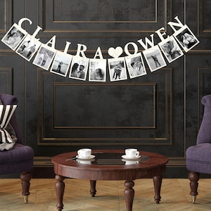 May include: A white photo banner with the names "CLAIRA" and "OWEN" separated by a heart. The banner is decorated with photos of a couple. The banner is hanging on a dark wall between two purple armchairs with striped cushions.