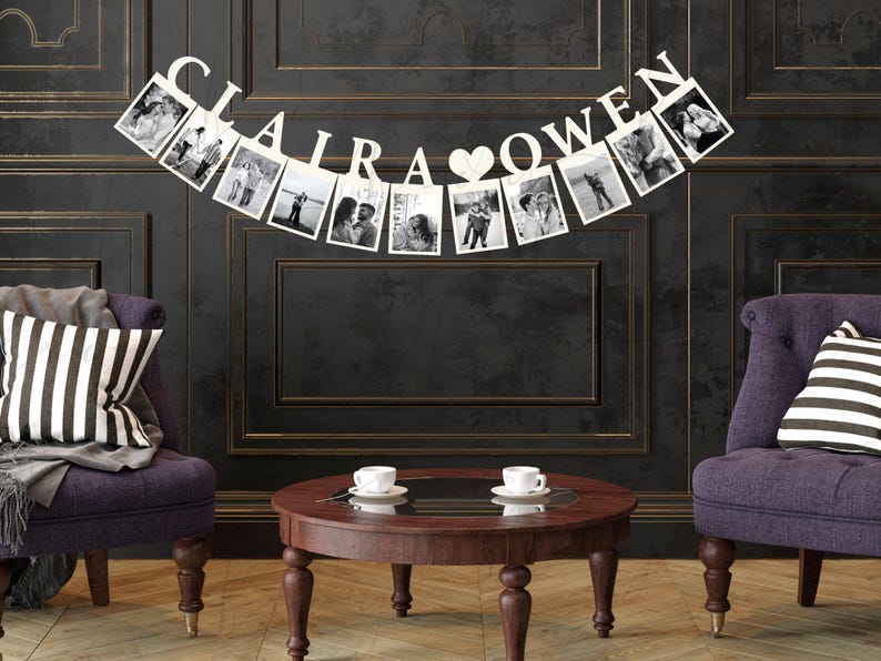 May include: A white photo banner with the names "CLAIRA" and "OWEN" separated by a heart. The banner is decorated with photos of a couple. The banner is hanging on a dark wall between two purple armchairs with striped cushions.