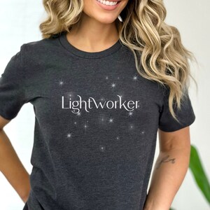 May include: A dark gray t-shirt with the text "Lightworker" in white lettering and a pattern of white stars.