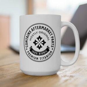 May include: White ceramic coffee mug with a black circle design that says "Contains Aftermarket Parts, Mostly Original, 100% Bionic, Premium Titanium".