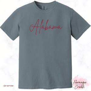May include: A gray t-shirt with the word "Alabama" written in red cursive script.