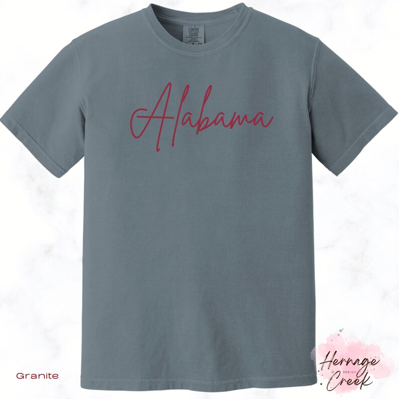 May include: A gray t-shirt with the word "Alabama" written in red cursive script.