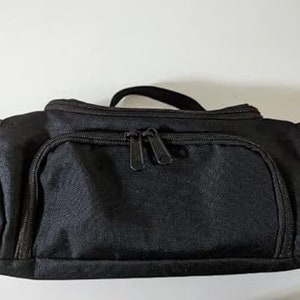 Può includere: Una borsa da viaggio nera con cerniera e manico superiore.
