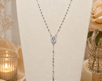 May include: A silver rosary necklace featuring diamond-cut beads, a central oval pendant depicting a figure, and a small crucifix at the bottom. The text LittleParisCo Diamond Cut Beads Rosary Silver Necklace is visible in the lower left corner.