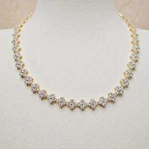 May include: A gold necklace with a delicate chain and small, clear cubic zirconia stones arranged in a flower pattern.
