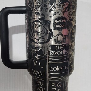 May include: Black travel mug with a silver floral and skull design. The mug has a black handle and lid. Text includes "you're mine", "my favorite color is grey", and "I want all the red flags".