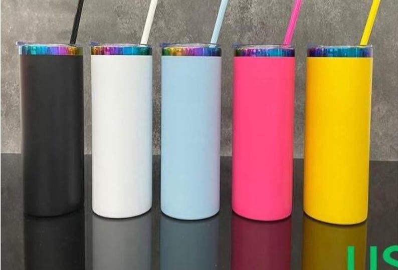 May include: Five colorful insulated tumblers with straws. The tumblers are black, white, light blue, pink, and yellow. Each tumbler has a rainbow-colored rim and a matching straw. The tumblers are cylindrical and appear to be made of metal.