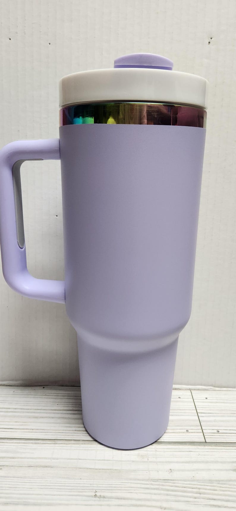 May include: A lavender travel mug with a white lid and a handle. The mug has a metallic iridescent band around the top.