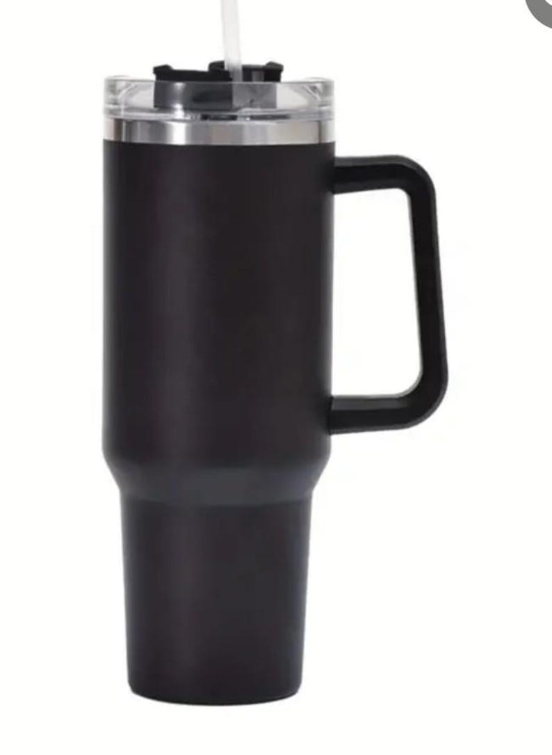 May include: Black stainless steel travel mug with a handle and a clear lid. The mug has a double-walled design to keep drinks hot or cold.