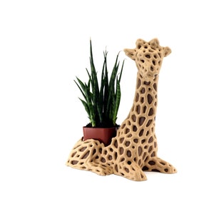May include: A brown giraffe-shaped planter with a green snake plant growing inside. The planter is made of a textured material that resembles a giraffe's skin.
