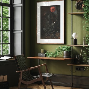 May include: A dark wood desk with a black metal frame and a green plant hanging over the edge. A black and brown woven chair sits in front of the desk. A framed print of a red flower hangs on the wall behind the desk.