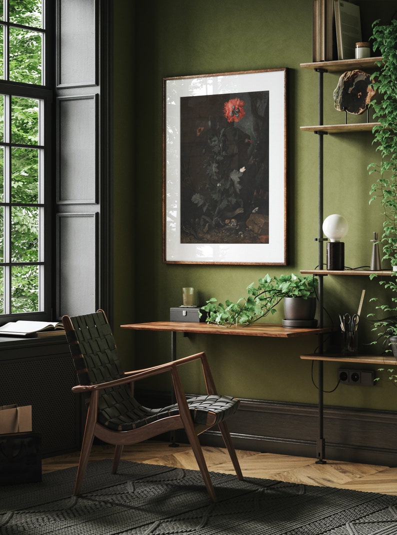 May include: A dark wood desk with a black metal frame and a green plant hanging over the edge. A black and brown woven chair sits in front of the desk. A framed print of a red flower hangs on the wall behind the desk.