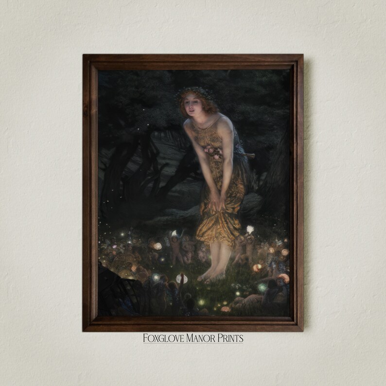 Op de afbeelding: Een ingelijst schilderij van een vrouw in een vloeiende gouden jurk die in een bos staat met gloeiende lichten. De vrouw wordt omringd door kleine figuren met gloeiende lichten. Het schilderij is getiteld "Foxglove Manor Prints".