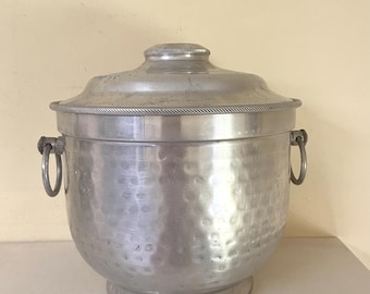 May include: A silver hammered aluminum ice bucket with a lid and two handles. The bucket has a textured surface and a round base.