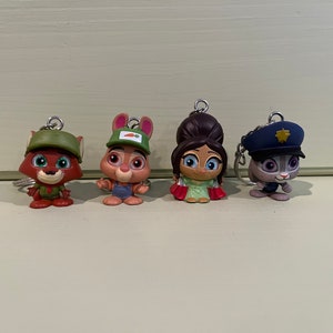May include: Four character keychains featuring animal figures. The characters include a fox in a green hat and uniform, a rabbit in overalls and a green hat, a woman in a green and red dress, and a rabbit in a police uniform.